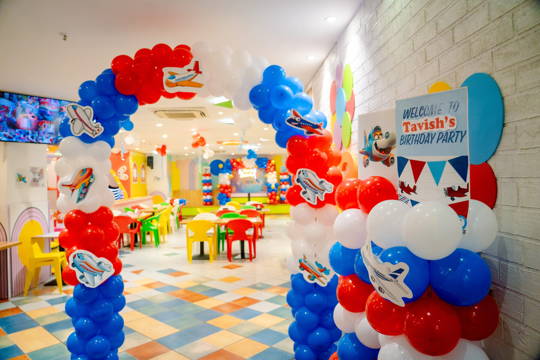Red, white and blue balloon arch welcoming guests into the Baccha Party Powai party hall
