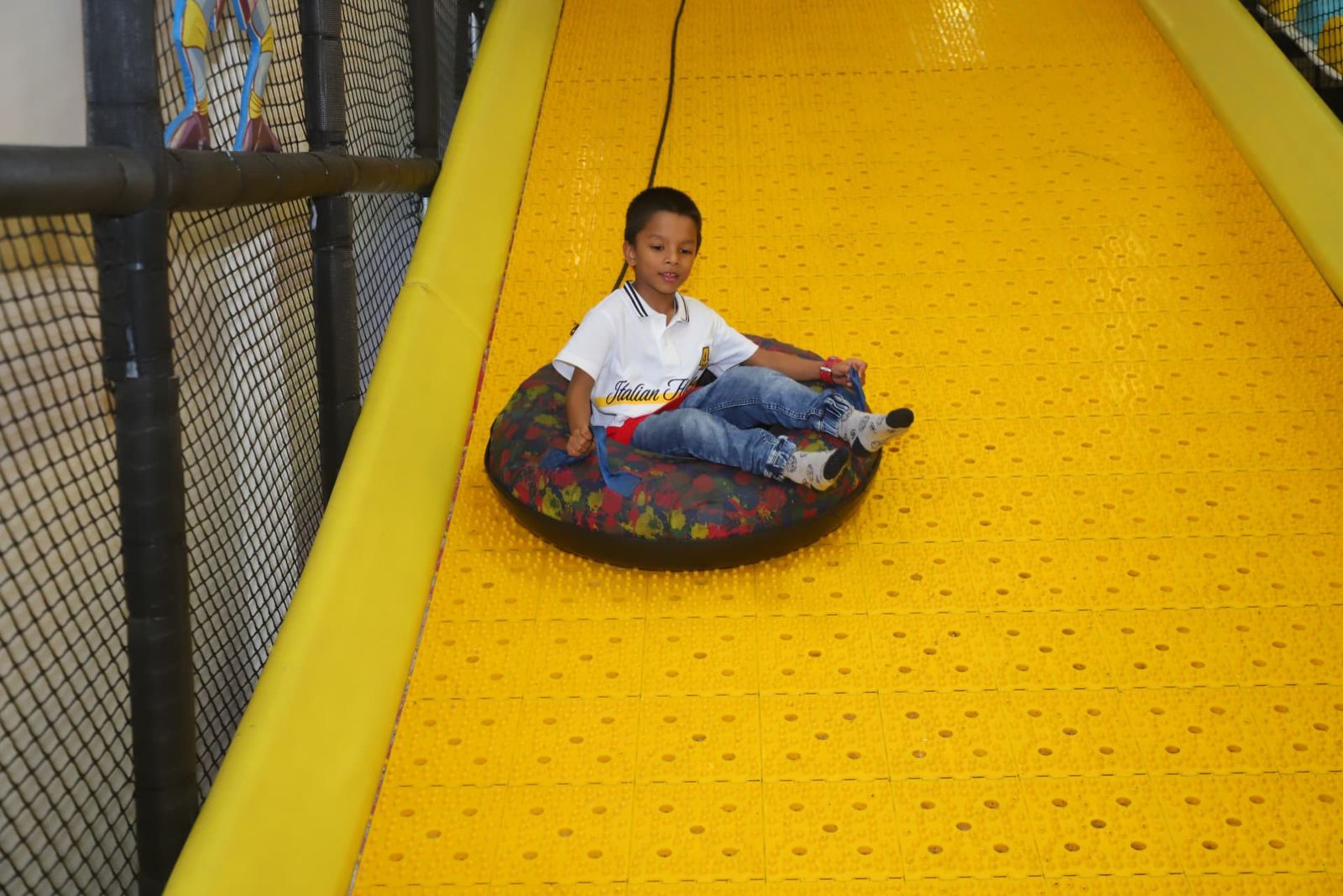 Boy riding a tube down the wide yellow slide at Baccha Party Thane