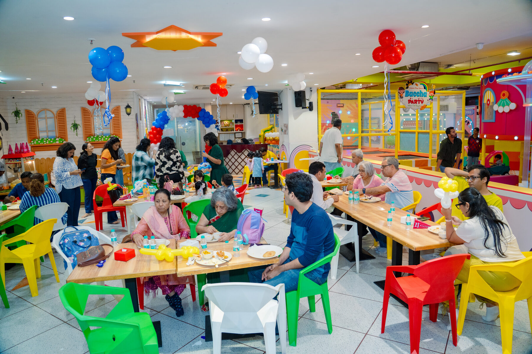 Families seated at colourful tables enjoying birthday buffet food at Baccha Party Powai