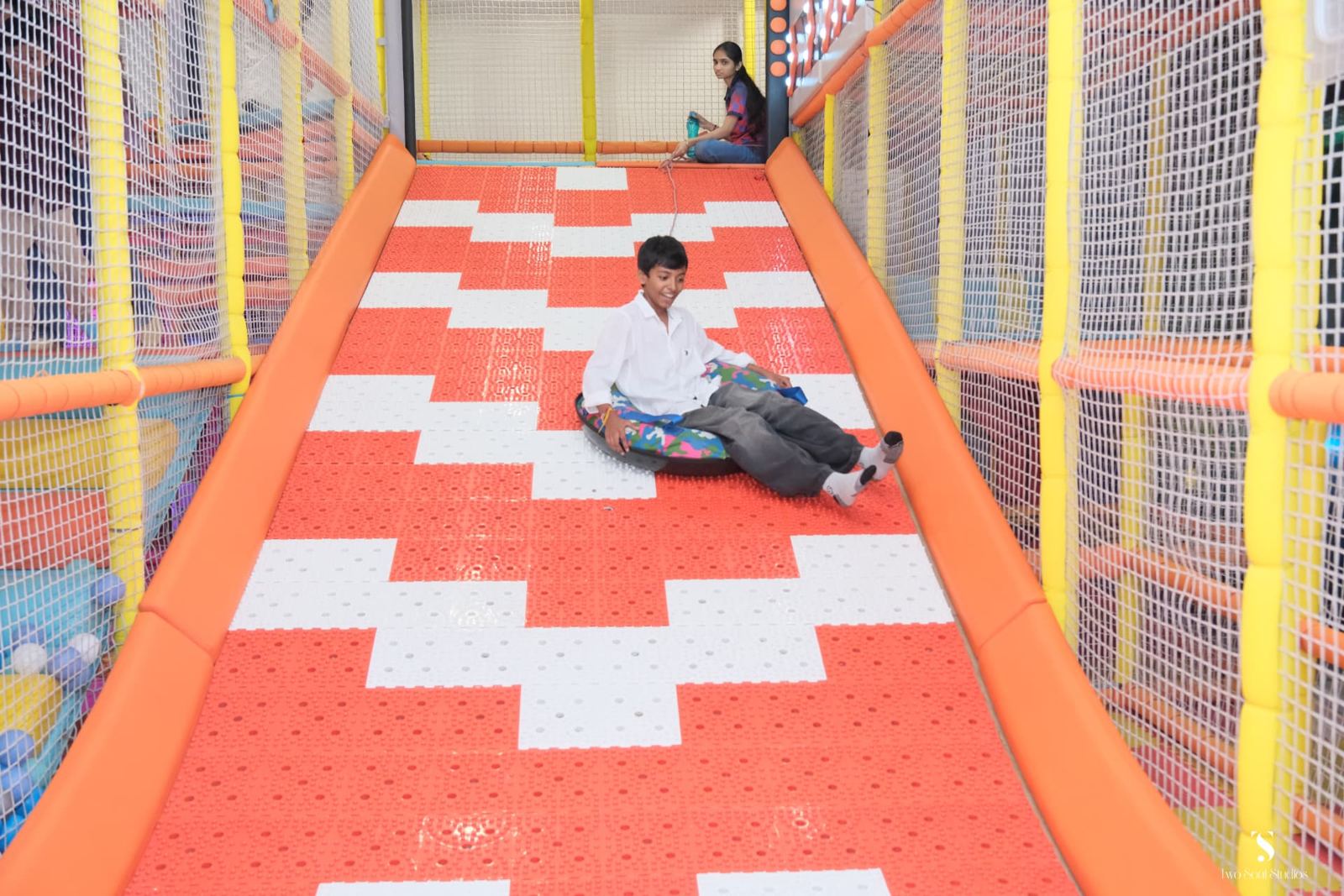 Boy riding a tube down the orange slide at Baccha Party Vashi