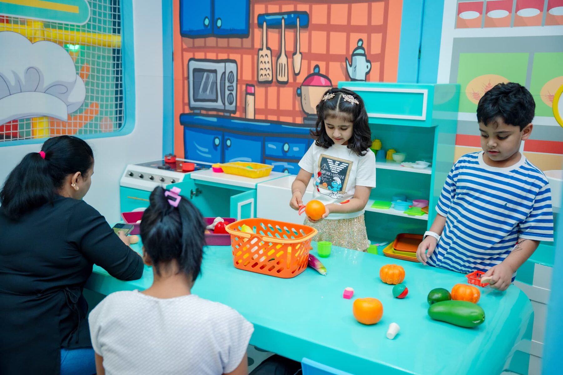 Children playing at the pretend-play kitchen at Baccha Party Powai
