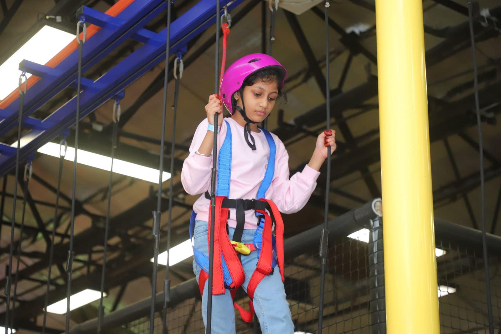 Girl in a helmet and harness on the rope course at Baccha Party Thane