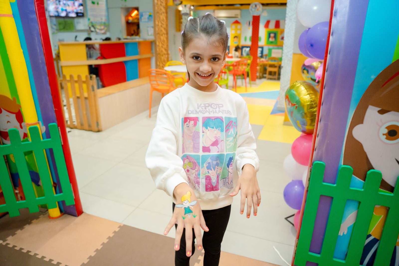 Child at the play-area gate with the café counter behind at Baccha Party Malad