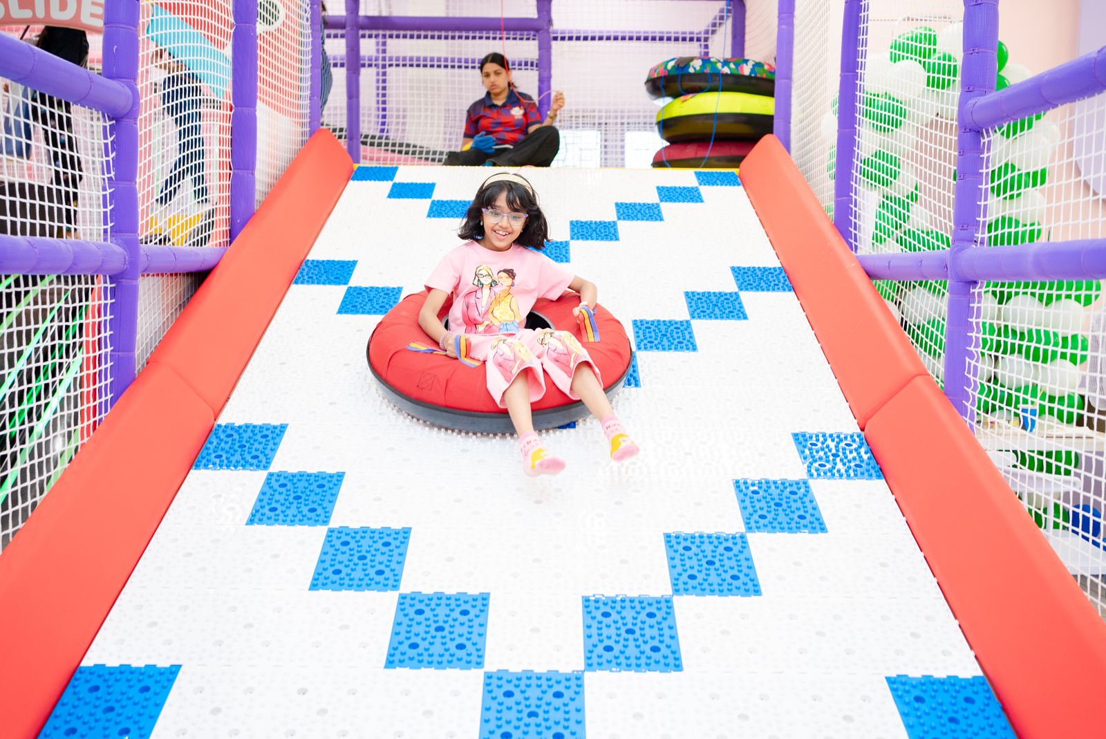 Girl riding a tube down the wide slide at Baccha Party Matunga