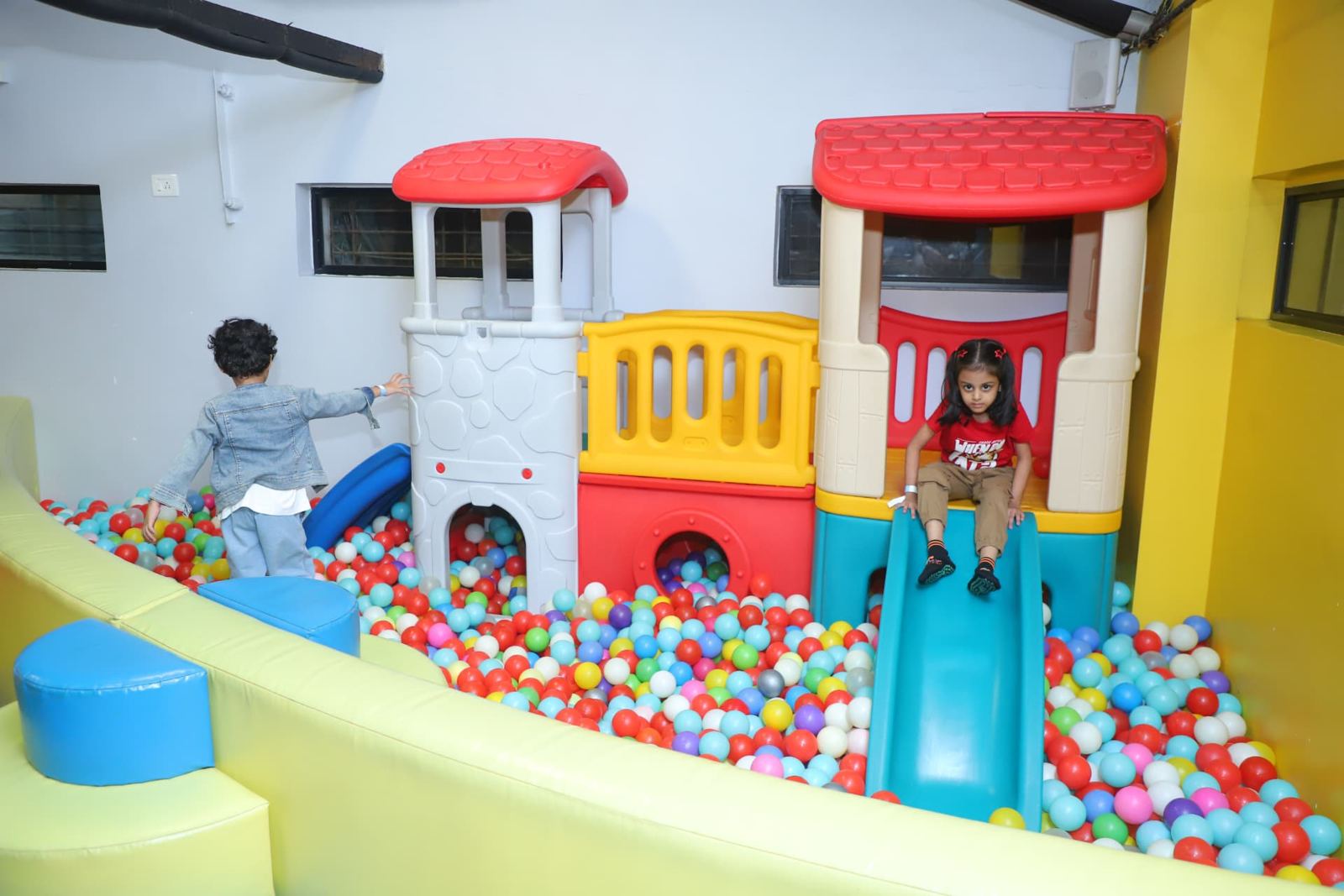 Toddlers on the mini slide and playhouse in the ball pit at Baccha Party Thane