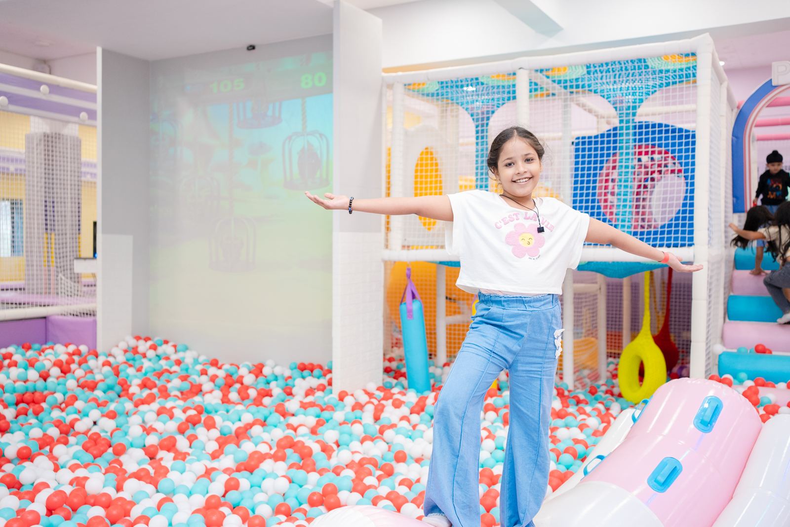 Girl balancing in the ball pit beside the play structure at Baccha Party Matunga