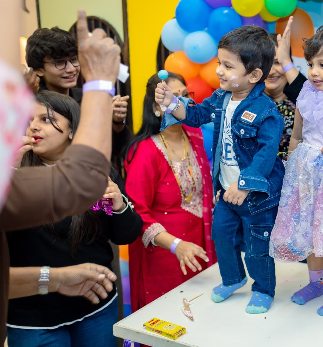 Family clapping and cheering around two small children during a birthday celebration at Baccha Party Matunga