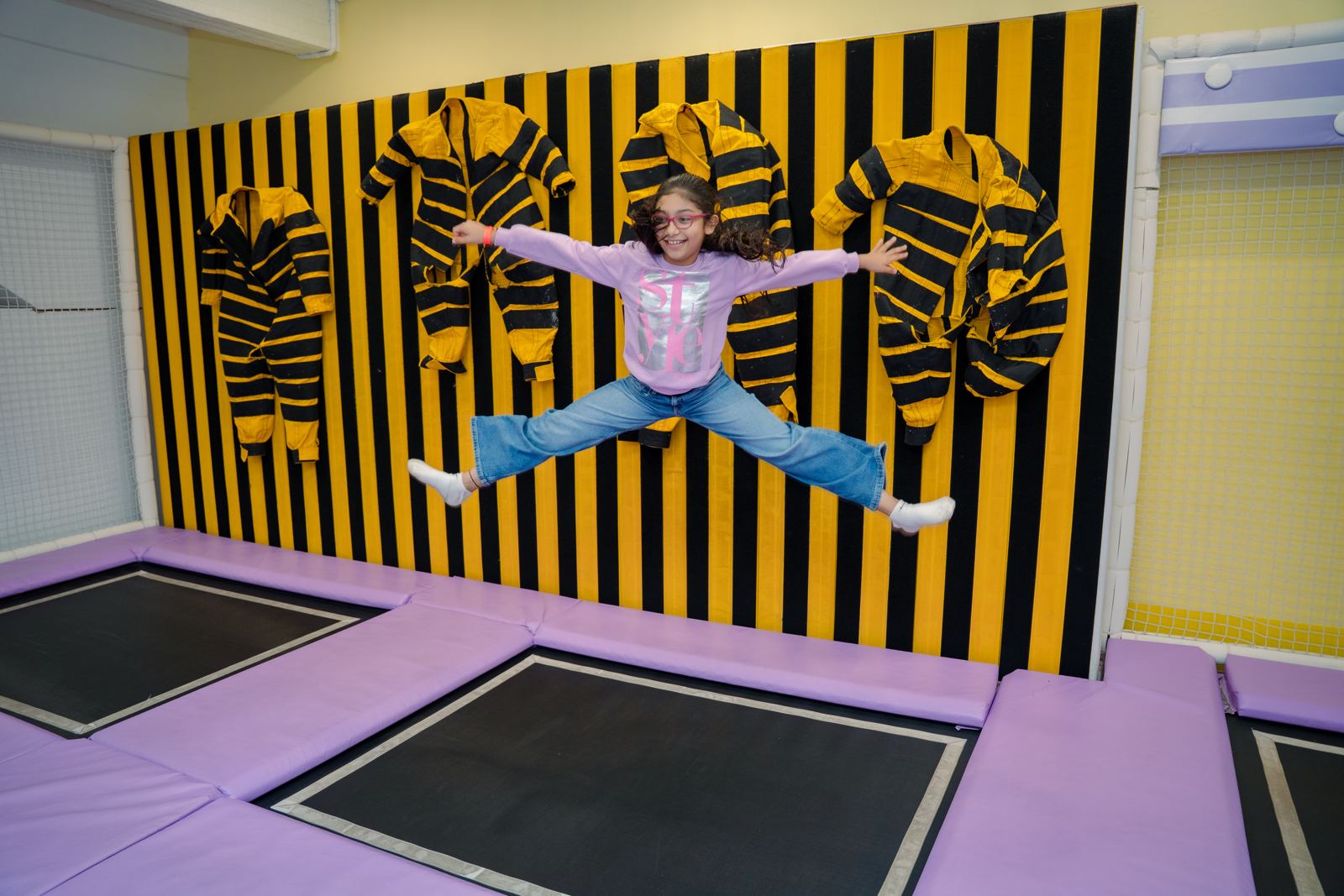 Girl leaping in front of the striped trampoline wall at Baccha Party Matunga
