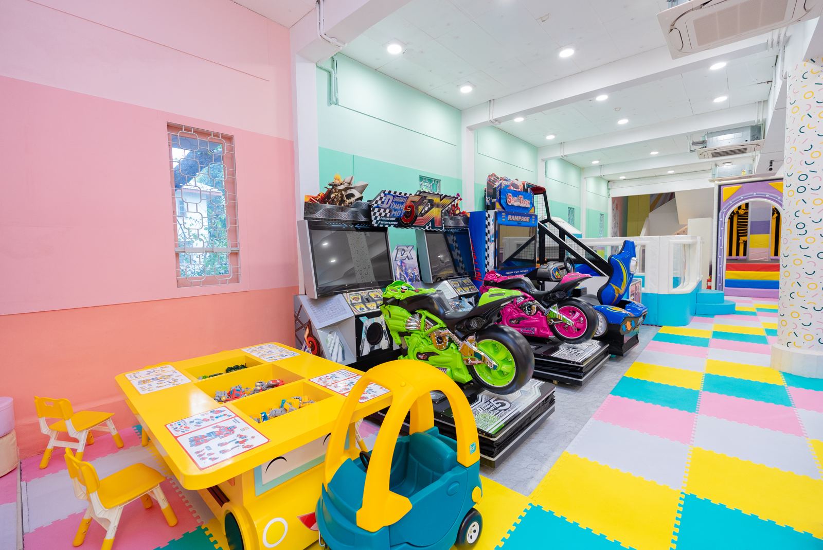 Ride-on arcade games beside a children's activity table at Baccha Party Matunga