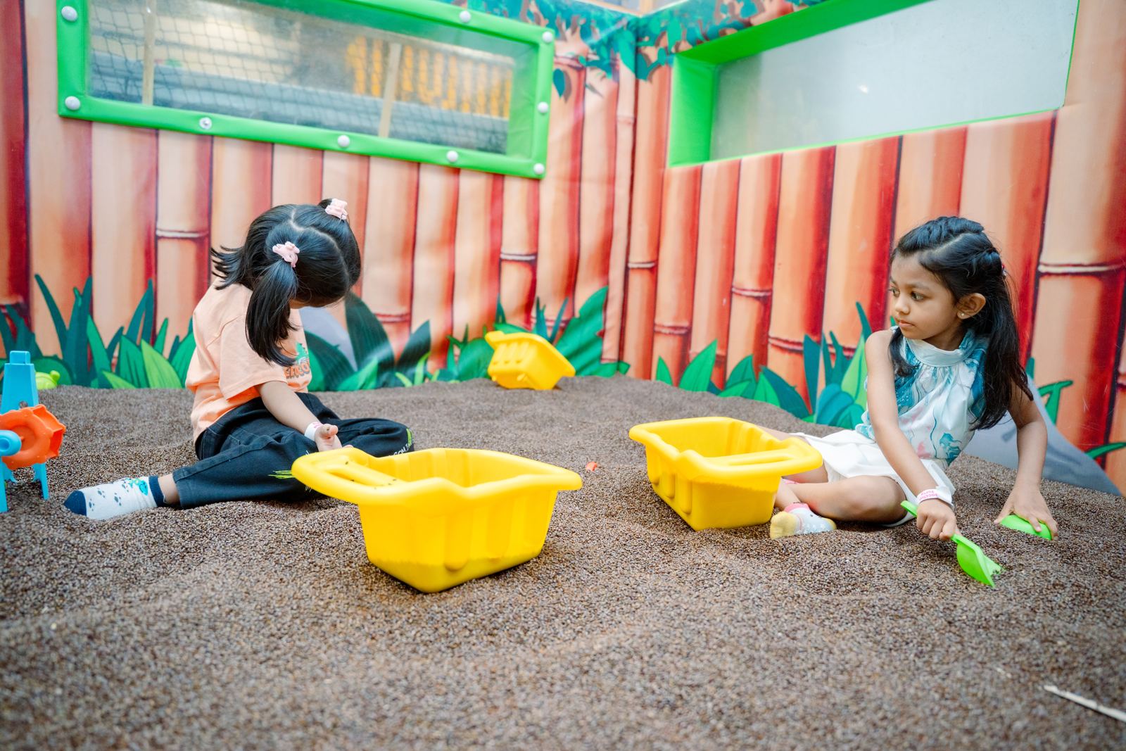 Two girls digging in the sand play area at Baccha Party Malad