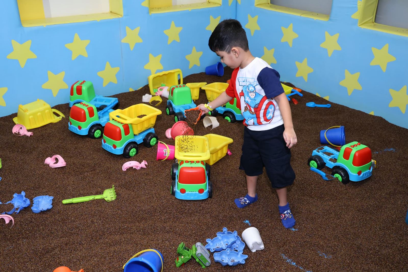 Boy playing with toy trucks in the sand play area at Baccha Party Thane
