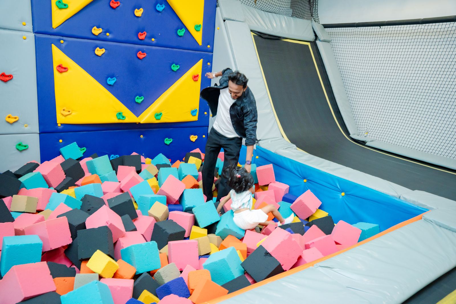 Parent and child in the foam pit below the climbing wall at Baccha Party Malad