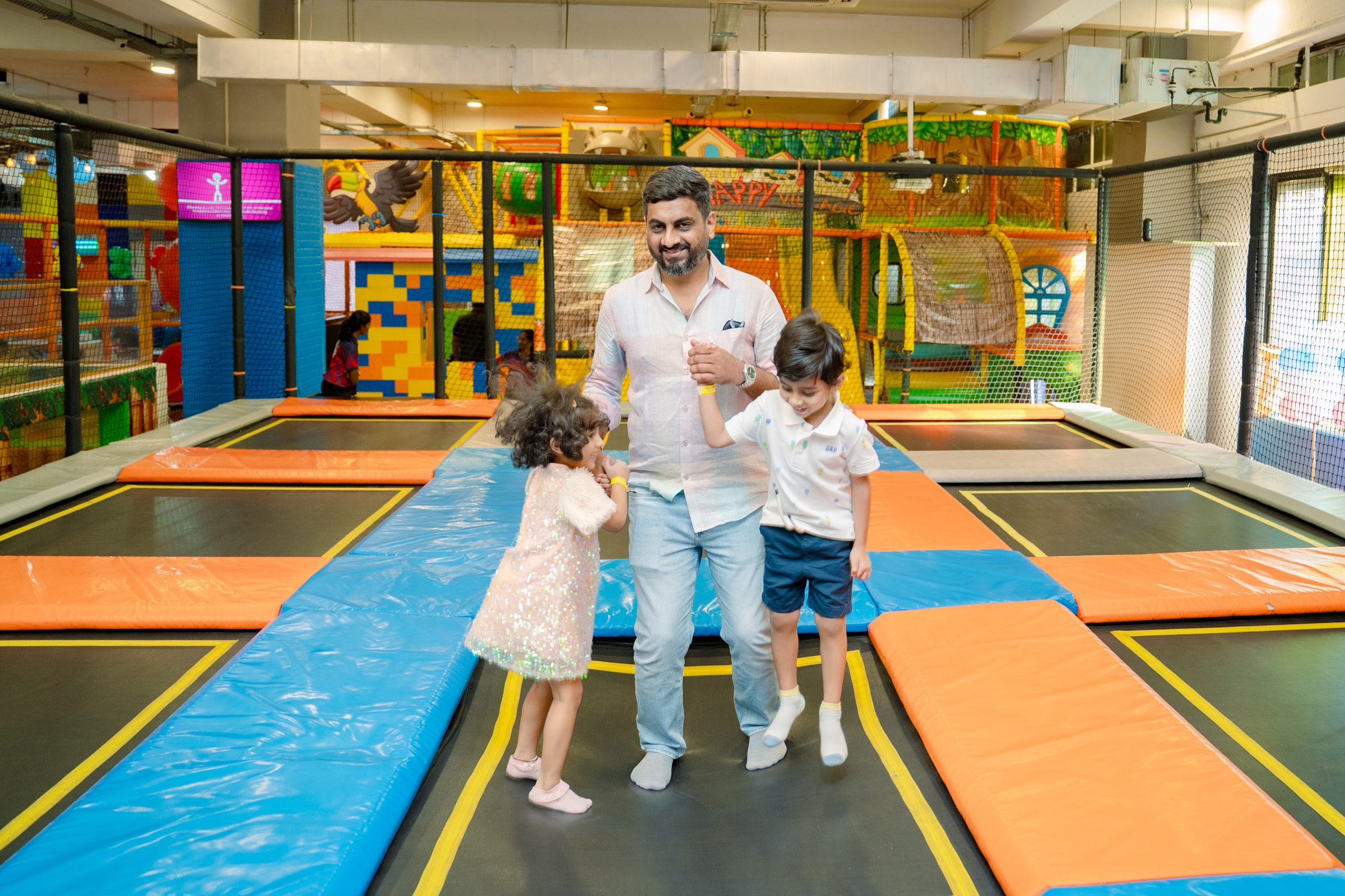 A parent playing alongside children on the trampolines at Baccha Party Malad