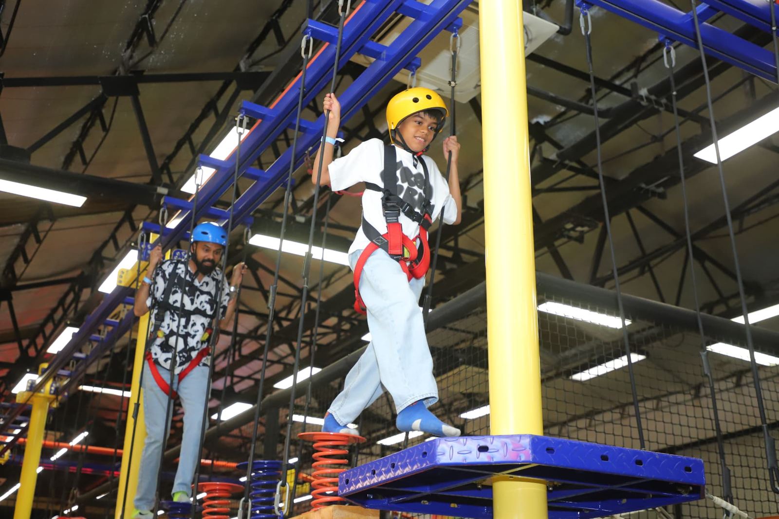 Children crossing the high rope course in harnesses at Baccha Party Thane